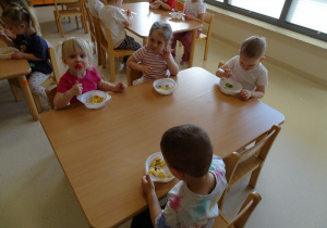 dzieci jedzą sałatkę owocową