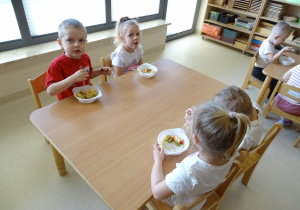 dzieci jedzą sałatkę owocową