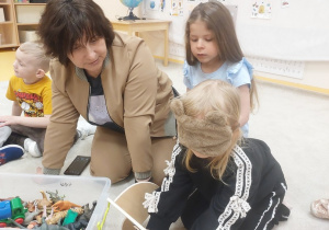 14. Inna dziewczynka przy nauczycielce dotyka zabawki schowanej w niebieskim woreczku
