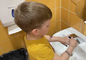 Chłopiec myje ręce według odpowiednich etapów.