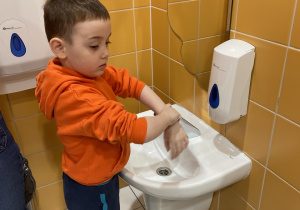 Chłopiec myje ręce według odpowiednich etapów.