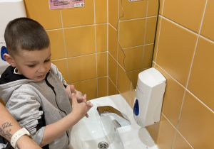 Chłopiec myje ręce według odpowiednich etapów.