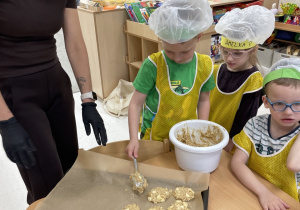 Pani z dziećmi nakłada ciastka na blaszkę.