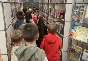 Dzieci oglądają regały z książkami.