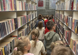 Dzieci oglądają regały z książkami.