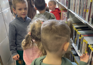 Dzieci oglądają regały z książkami.