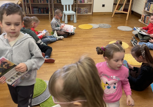 Dzieci oglądają książki w bibliotece.