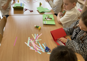 Dzieci wykonują kartki wielkanocne z życzeniami dla rodziców.
