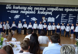 dzieci ubrane na galowo śpiewają piosenkę