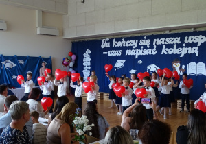 Dzieci tańczą z czerwonymi balonami w kształcie serca