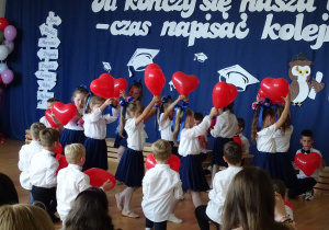 Dzieci tańczą z czerwonymi balonami w kształcie serca