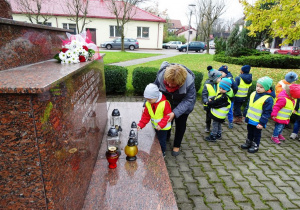 Dzieci składają znicze pod pomnikiem 