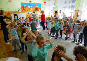 Dzieci tanczą w kole trzymając się za głowy