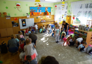 Dzieci tańczą w kole trzymając się za kostki