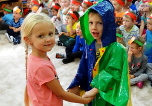 Chłopiec w kolorowej pelerynie przeciwdeszczowej z dziewczynką