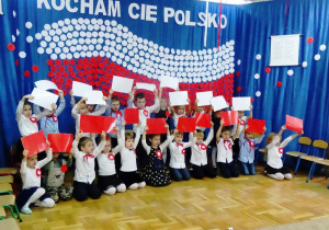 Dzieci z białych i czerwonych kartek ułożyły flagę Polski