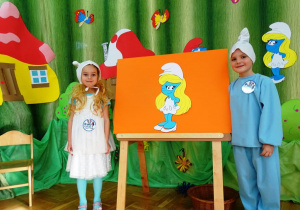 Chłopczyk i dziewczynka stoją przy portrecie smerfetki