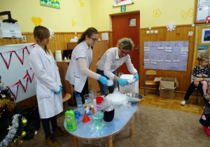 Nauczyciel chemii z uczennicami demonstruje doświadczenie z suchym lodem