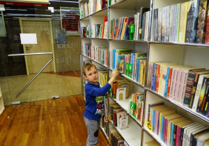 Chłopiec zdejmuje książkę z półki