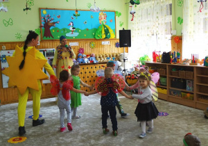 Dzieci przebrane za wiosenne owady tańczą w kółeczku