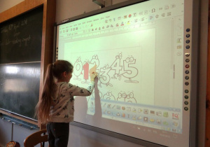 Dziewczynka koloruje na tablicy interaktywnej