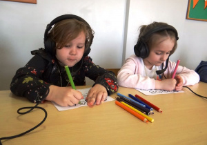 Dziewczynki w słuchawkach na uszach wykonują polecenia lektora