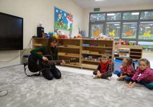 Dzieci słuchają dźwięków gitary.