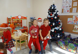 Szymon i Zosia pozują do zdjęcia z Mikołajem.