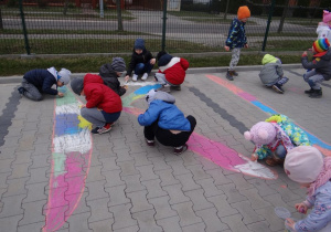 Przedszkolaki kolorują litery na kostce