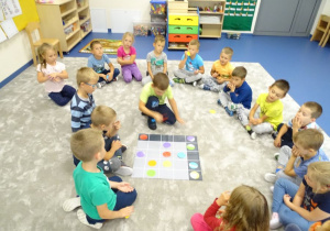 Dzieci wspólnie na dywanie układają sudoku na macie.