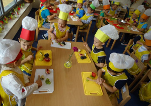 Dzieci kroją wybrane owoce na deskach do krojenia.