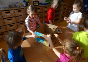 Dzieci malują farbami pudełko