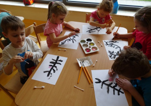 Dzieci malują farbami gałązkę wiśni