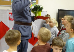 Dzieci i Piłsudski salutują.