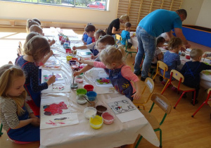 Pan pomaga dzieciom przy malowaniu