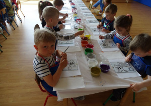Dzieci w skupieniu malują na szkle