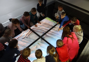 Dzieci oglądają plany związane z odkrywką Bełchatów.