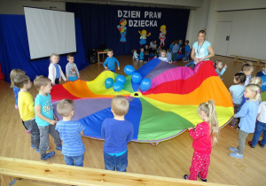 Dzieci podrzucaja na chuście animacyjnej niebieskie balony