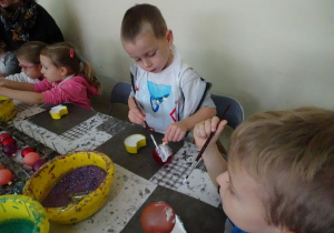 Dzieci malują bombkę klejem