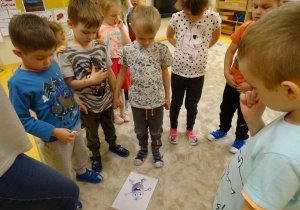 Dzieci stoją wokół ilustracji Pastusia
