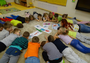 Dzieci leżą na podłodze wokół ilustracji Pastusiów