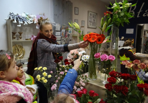 Dzieci razem z panią florystką wybierają kwiaty.
