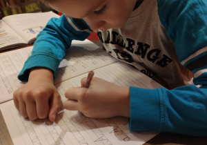 Daniel ćwiczy pisanie literki "A".