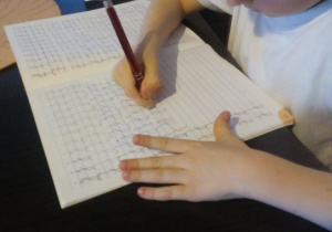 Filipek ćwiczy pisanie litery "J".