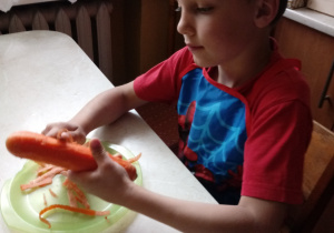Szymuś obiera marchewkę.
