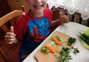 Szymon wykonuje przekąskę z marchewek, sałaty i pietruszki.