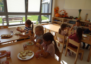 Dzieci podczas podwieczorku jedzą upieczone przez siebie muffiny.