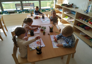 Dzieci wykonują pracę w książce wykorzystując dary jesieni.