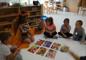 Pani Jesień pokazuje dzieciom dary jesieni.