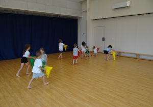 Dzieci biegają po sali zbierając liście (woreczki) do koszyczków (czyli pachołków).